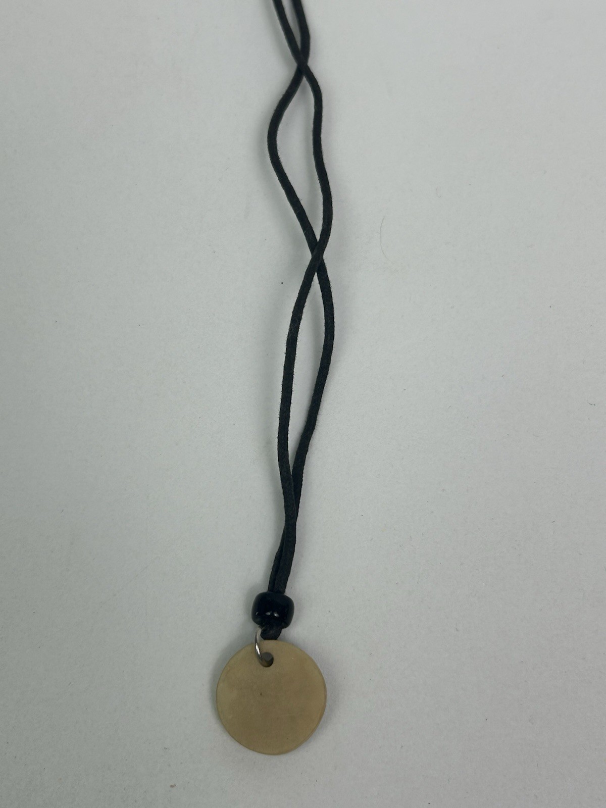 Vintage black cord necklace features a green pendant with “Groovy” inscribed