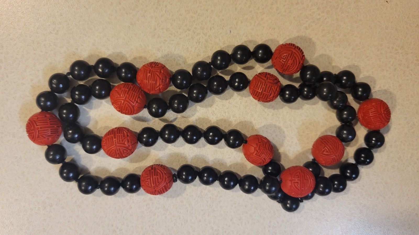 Cinnabar and black obsidion necklase 30″ hand knotted no clasp. 11 carved red lg
