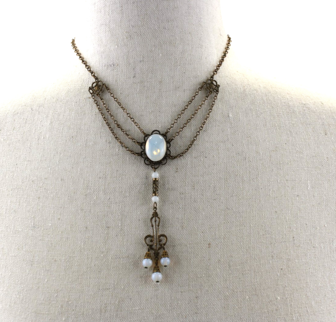 Vintage Style Stamp Brass Festoon Necklace Features an iridescent faux moonstone