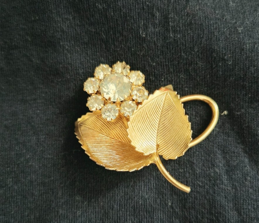 Vintage gold brooch w/two textured leaves and a cluster of clear faceted stones