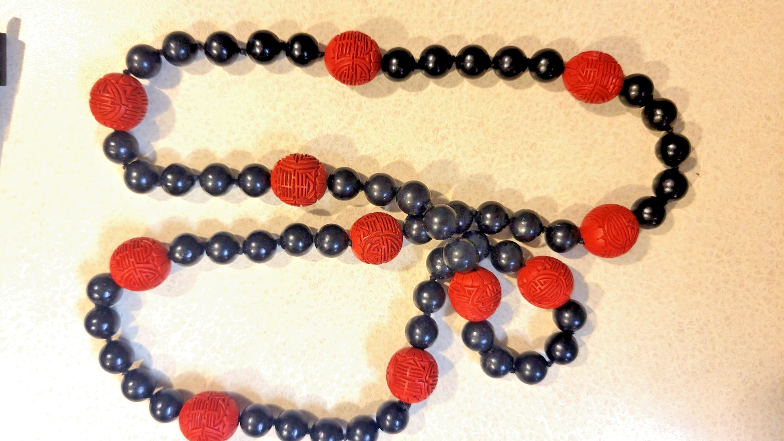 Cinnabar and black obsidion necklase 30″ hand knotted no clasp. 11 carved red lg