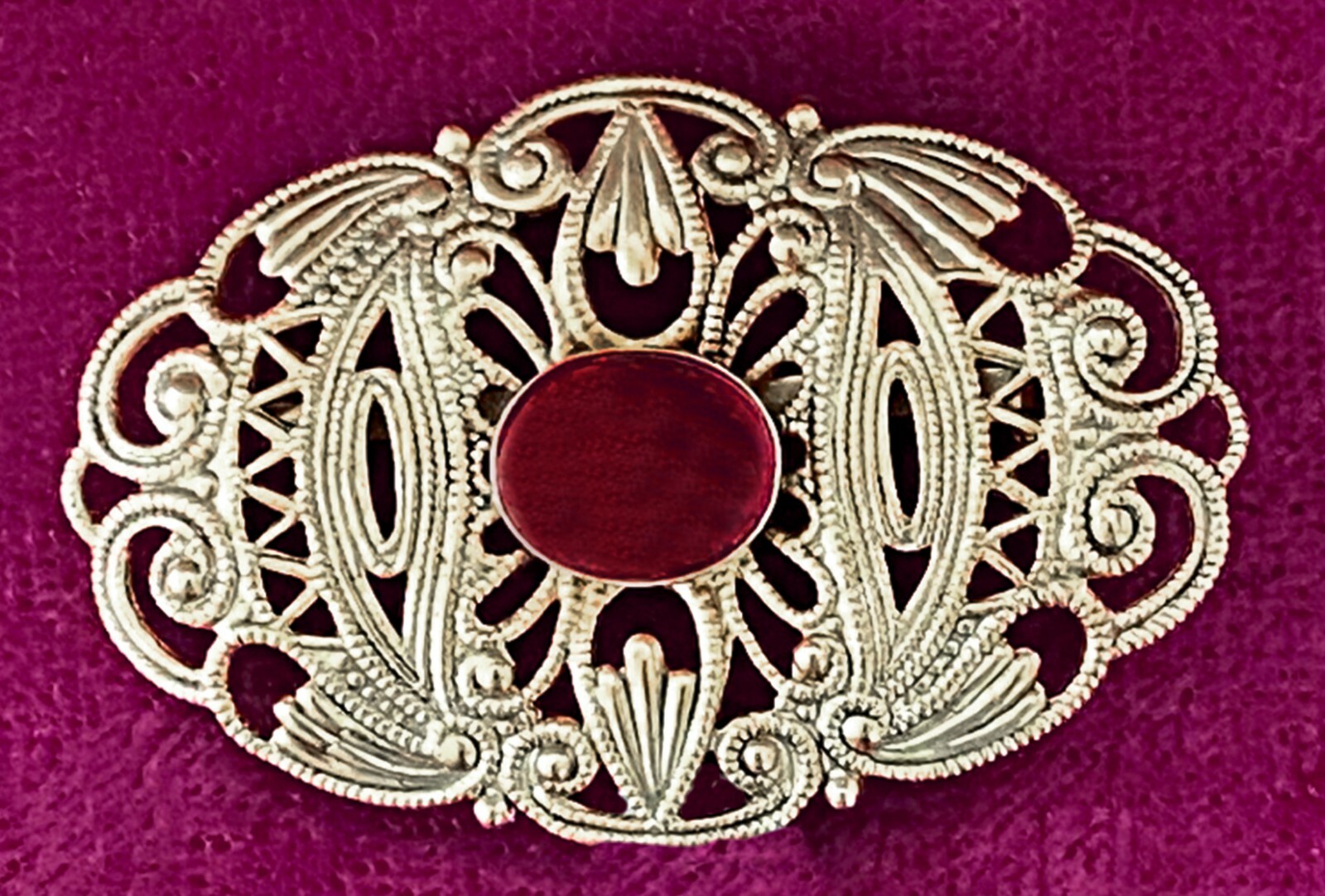 GOLD COLORED METAL BROOCH WITH RED STONE
