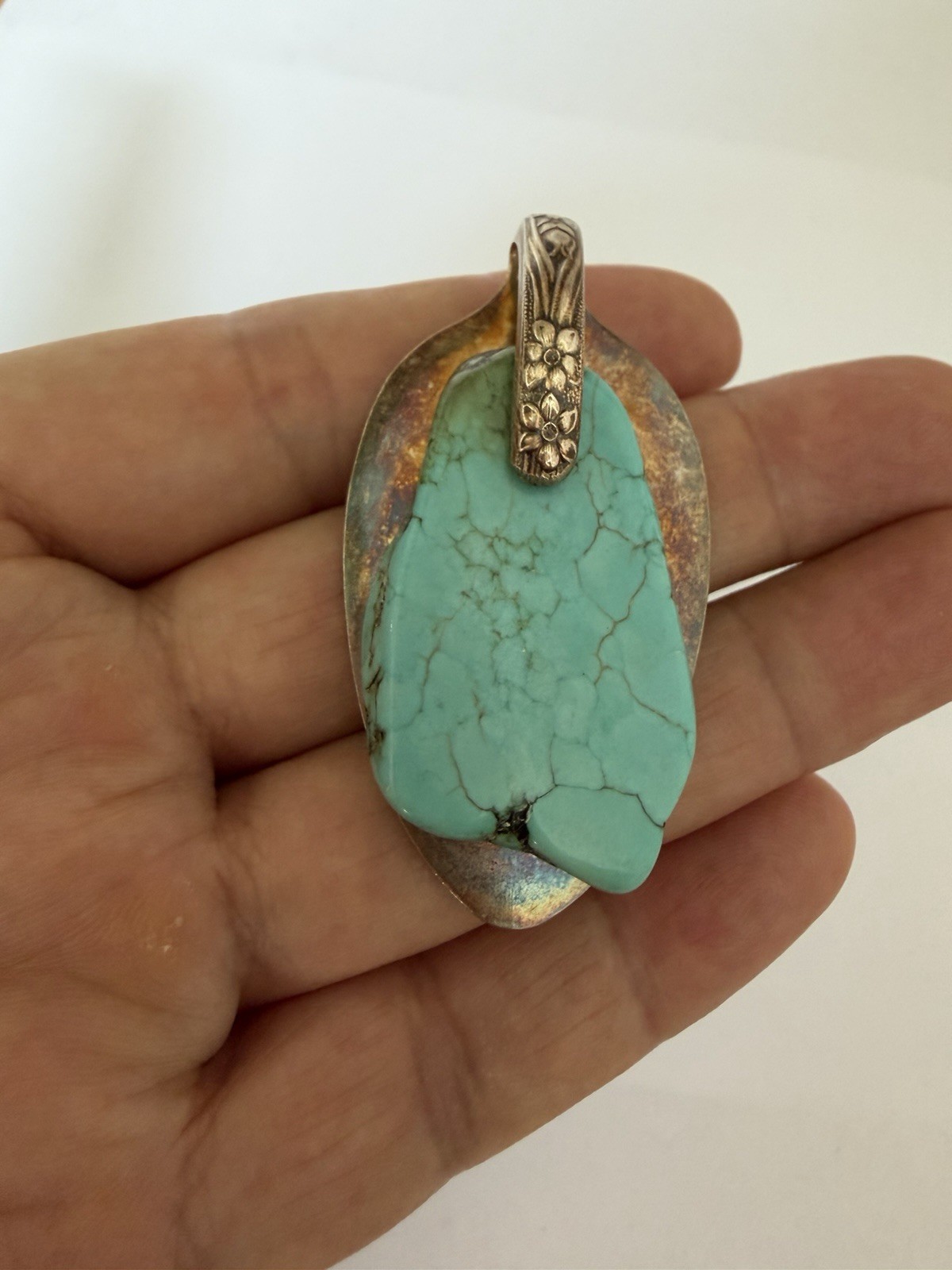 Beautiful silver pendant featuring a turquoise stone set on a decorative bail B5