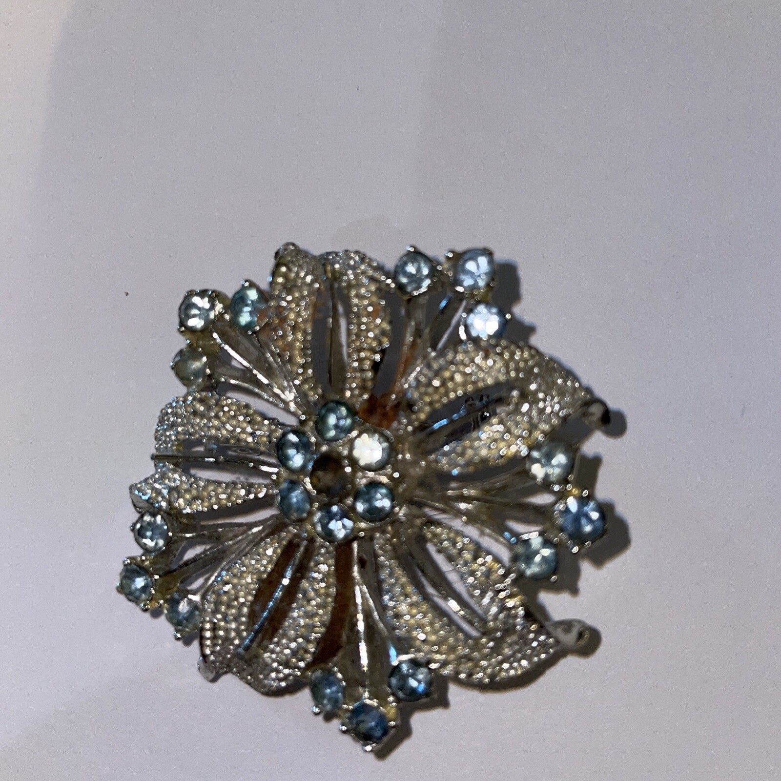 Silver-tone flower brooch w/ pale blue stones (center stone missing)–preowned